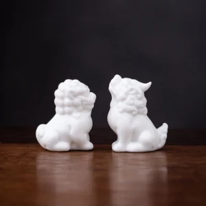 group of cute white ceramic lion tea pets on a wooden tea table, tea pet collection