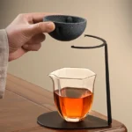 dark gray frosted porcelain tea strainer with black metal stand on wood table