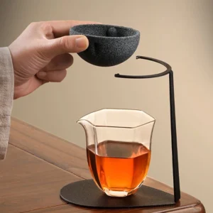 dark gray frosted porcelain tea strainer with black metal stand on wood table