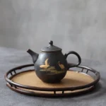 full side view of handmade chinese black ceramic teapot with golden crane pattern