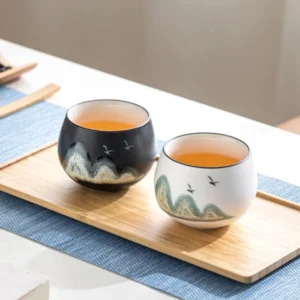 Hand-painted mountain and bird Chinese tea cup on traditional tea mat