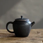 full view of handcrafted textured bark black chinese teapot with built-in stainless steel infuser