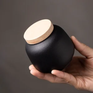 matte black ceramic tea canister with natural wood lid front view