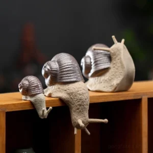 large and small realistic ceramic snail tea pet displayed on wooden shelf, decorative chinese tea accessory