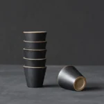set of 6 rustic dark chinese ceramic tea cups stacked on wooden board