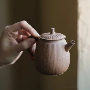 full side view of vintage handmade chinese old clay teapot with curved handle